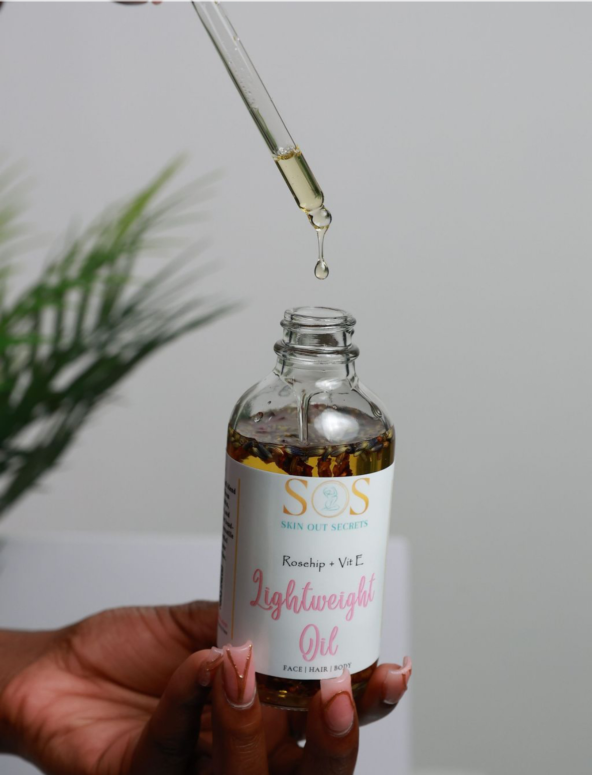 Skin Out Secrets Lightweight Oil with rosehip and vitamin E, dropper releasing a golden drop